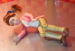 Doll, action figure, fem-character in pink top and white shirt with khaki/beige